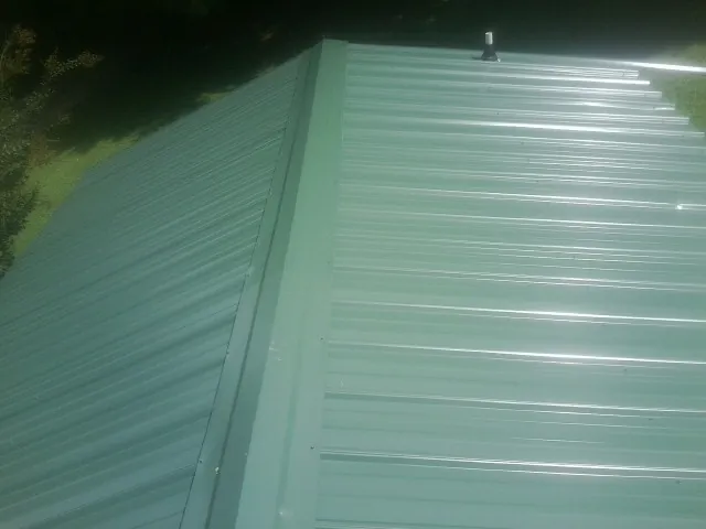 New green metal panels meeting at the ridge of a roof — Flat Roof Repair work by our crew in Silver Springs