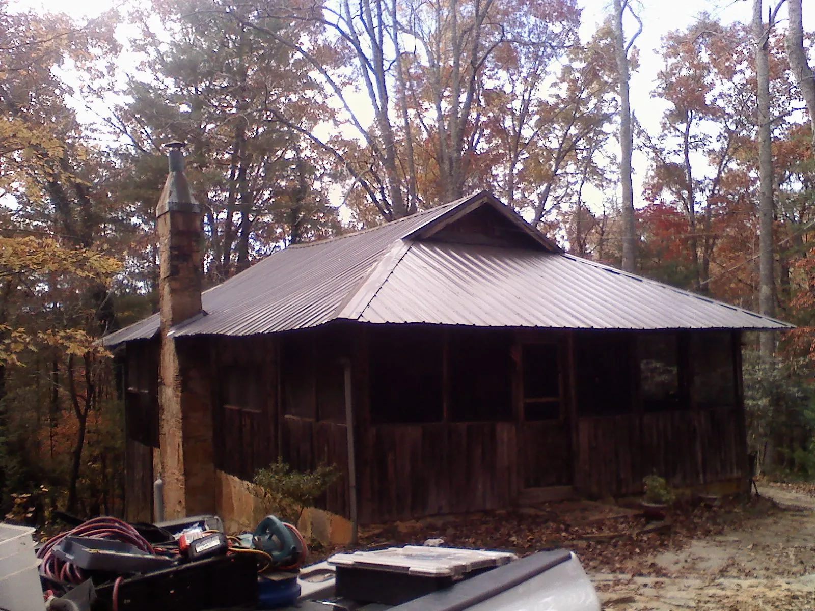 Brown metal hip roof on an old cabin with a stone chimney in Silver Springs