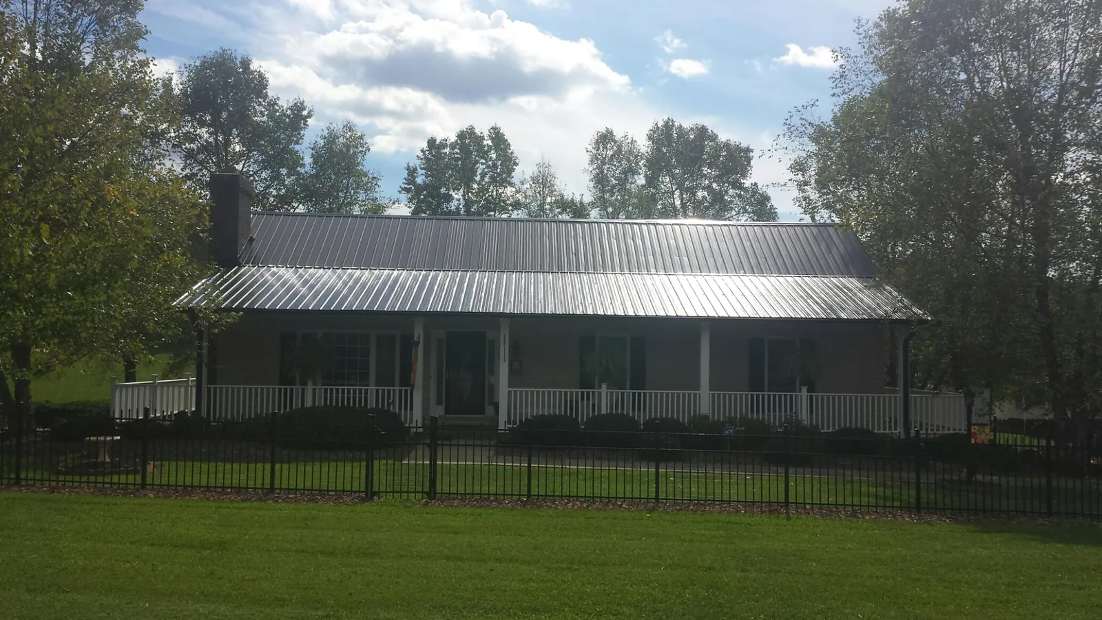 Gray metal roof on a brick ranch with a full width front porch — Gutter Guard Installation work by our crew in Silver Springs